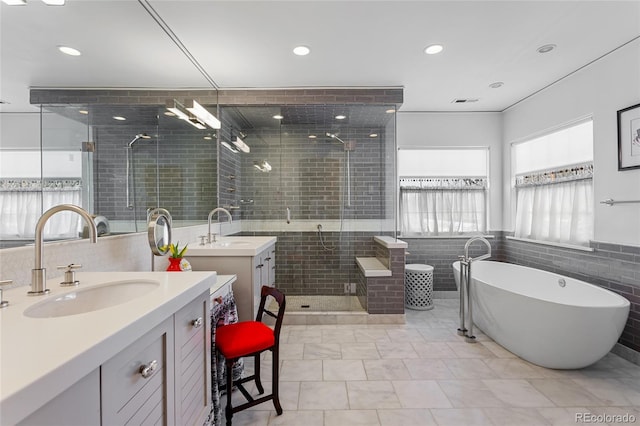 full bath with a freestanding bath, a shower stall, two vanities, and a sink