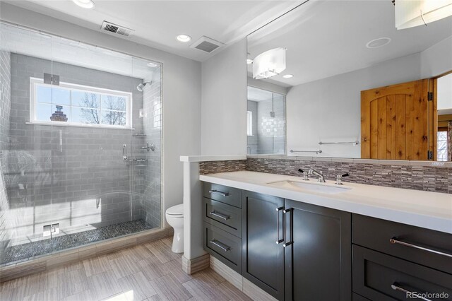 full bath featuring tasteful backsplash, a shower stall, toilet, and visible vents