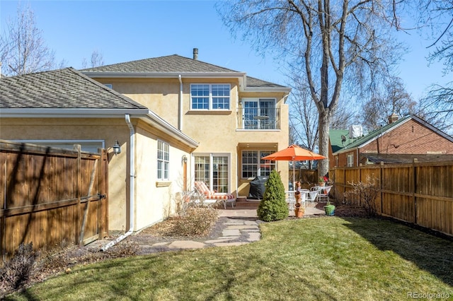 back of house featuring roof with shingles, a fenced backyard, stucco siding, a patio area, and a lawn