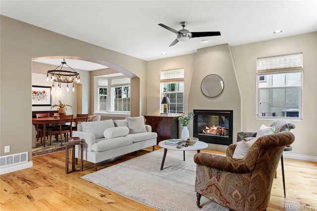 2411 S Milwaukee St, Denver, CO 80210 - living area featuring light wood-style flooring, ceiling fan, arched walkways, a large fireplace, and baseboards