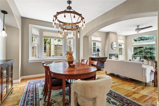 2411 S Milwaukee St, Denver, CO 80210 - dining space with arched walkways, light wood-type flooring, a fireplace, baseboards, and ceiling fan