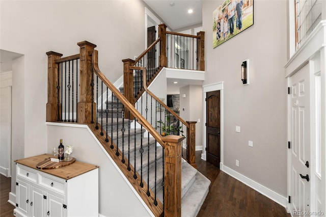 stairway featuring recessed lighting, baseboards, wood finished floors, and a towering ceiling