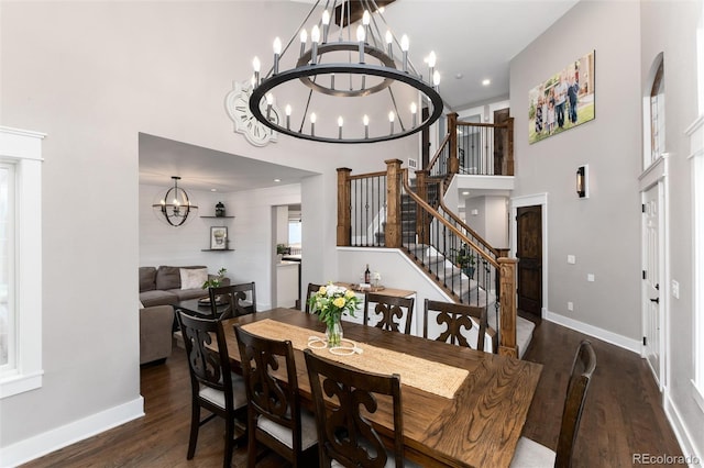 dining area featuring wood finished floors, baseboards, a high ceiling, stairs, and a chandelier