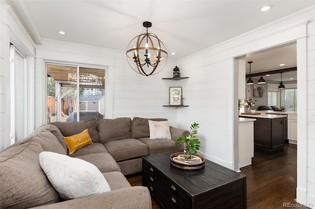 living room with recessed lighting, an inviting chandelier, dark wood-style floors, and ornamental molding