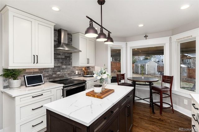 kitchen with light stone countertops, dark wood-style flooring, stainless steel range with electric cooktop, wall chimney exhaust hood, and backsplash