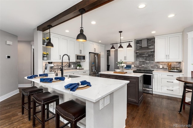 kitchen with dark wood-style floors, a kitchen island, a sink, stainless steel appliances, and wall chimney exhaust hood