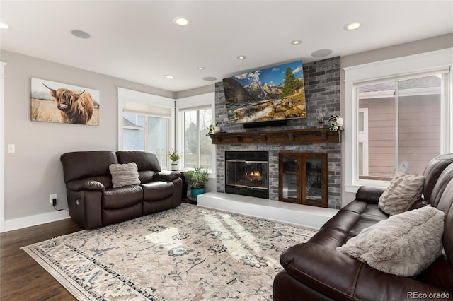 living area with recessed lighting, a brick fireplace, baseboards, and wood finished floors