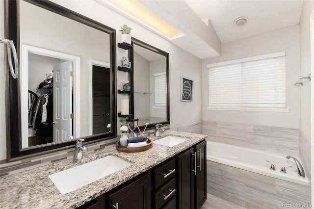 full bath with double vanity, a bath, and a sink