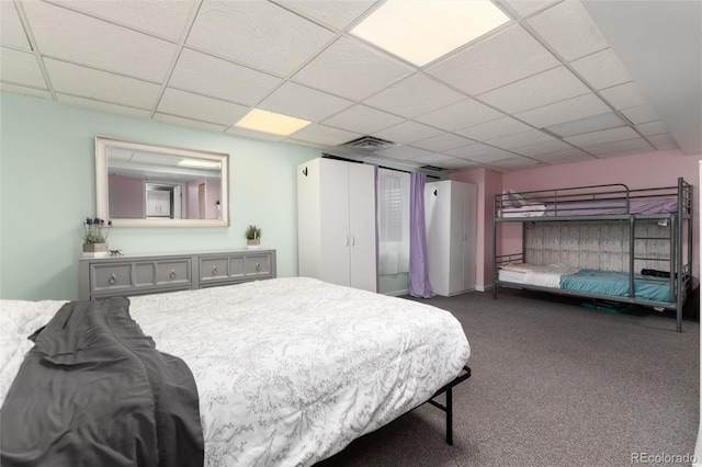 carpeted bedroom with a drop ceiling and visible vents