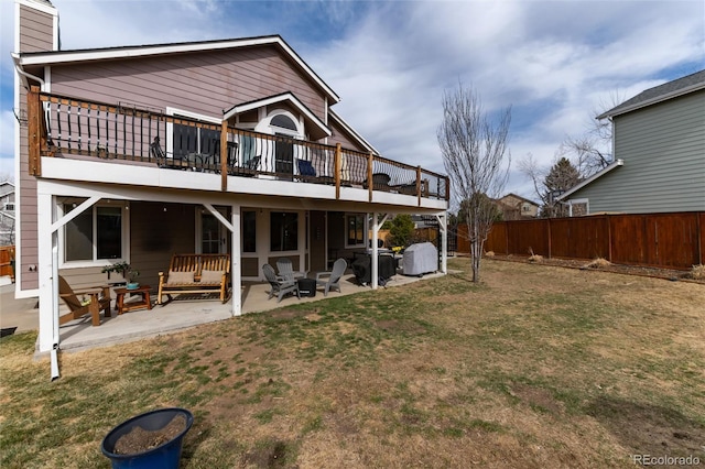 rear view of house with fence, a lawn, a chimney, a deck, and a patio area