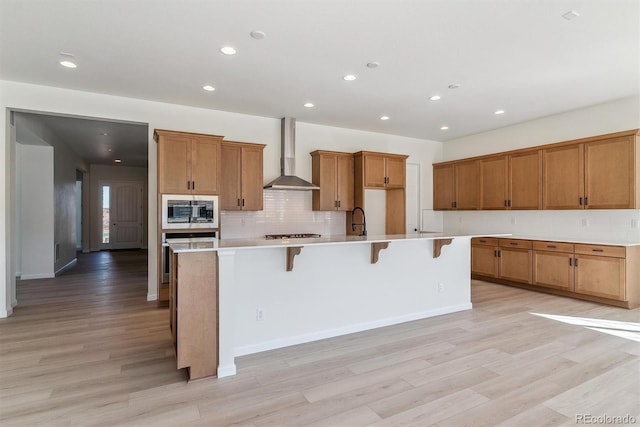 kitchen with a kitchen breakfast bar, built in microwave, a spacious island, and wall chimney range hood