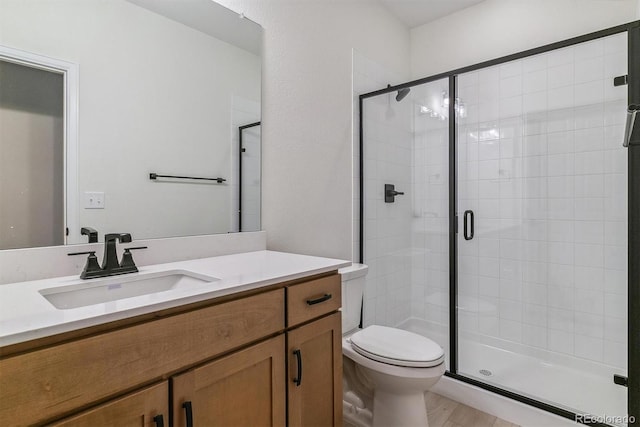 bathroom featuring hardwood / wood-style floors, vanity, a shower with shower door, and toilet