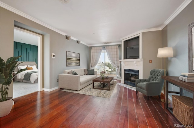 living area with baseboards, visible vents, a fireplace with flush hearth, ornamental molding, and wood finished floors