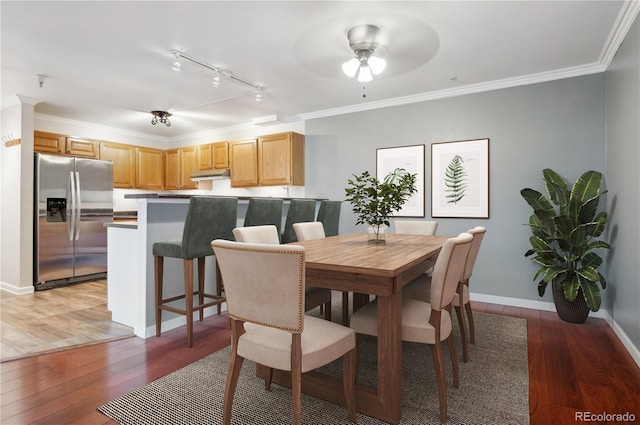 dining space featuring rail lighting, ceiling fan, crown molding, and dark wood-type flooring