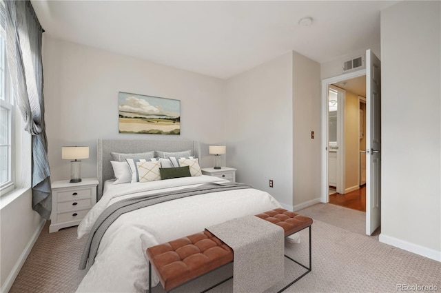 bedroom featuring baseboards, visible vents, and light colored carpet