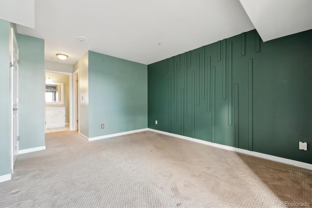 empty room featuring baseboards and light colored carpet