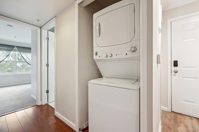 laundry area with hardwood / wood-style flooring and stacked washer / dryer