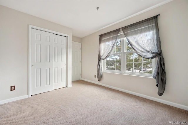 unfurnished bedroom with carpet floors, a closet, and baseboards