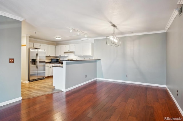 kitchen with stainless steel appliances, ornamental molding, a peninsula, under cabinet range hood, and hardwood / wood-style flooring