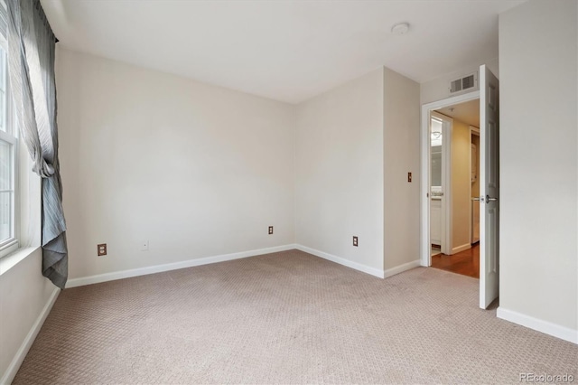 spare room featuring carpet flooring, visible vents, and baseboards