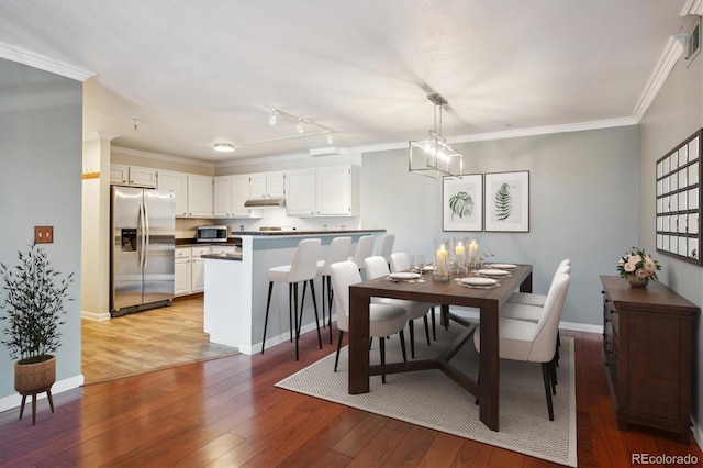 dining room with a notable chandelier, light wood-style flooring, baseboards, and crown molding