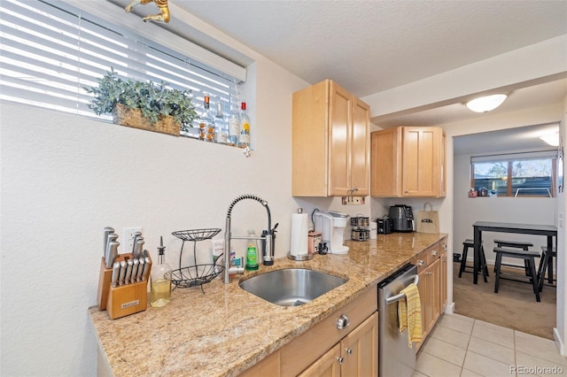 kitchen featuring dishwasher, light stone counters, a textured ceiling, light brown cabinets, and a sink