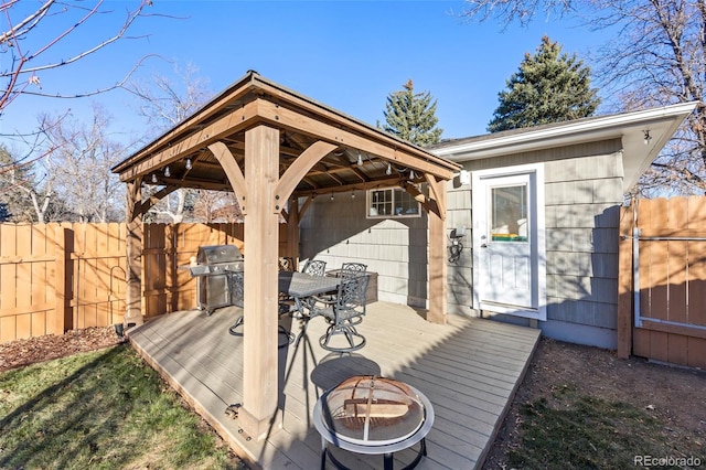 wooden deck with fence, a fire pit, and area for grilling