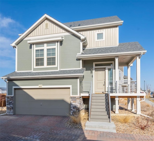 view of front of house with board and batten siding, stone siding, a shingled roof, and decorative driveway