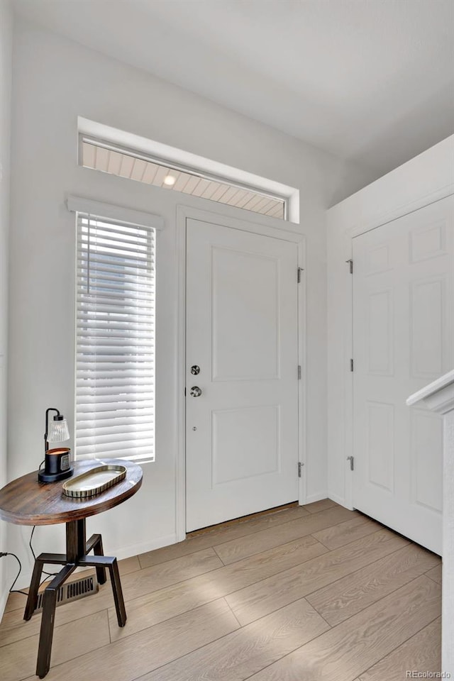 foyer with light wood-style flooring and baseboards