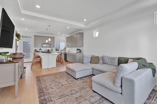 living area featuring light wood-type flooring, a raised ceiling, and recessed lighting