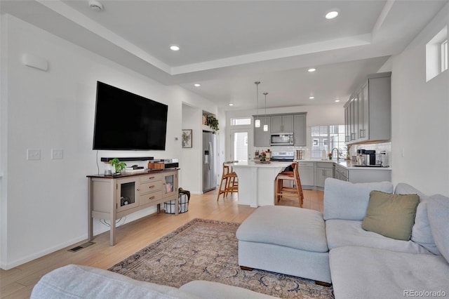 living room with light wood-type flooring, baseboards, visible vents, and recessed lighting