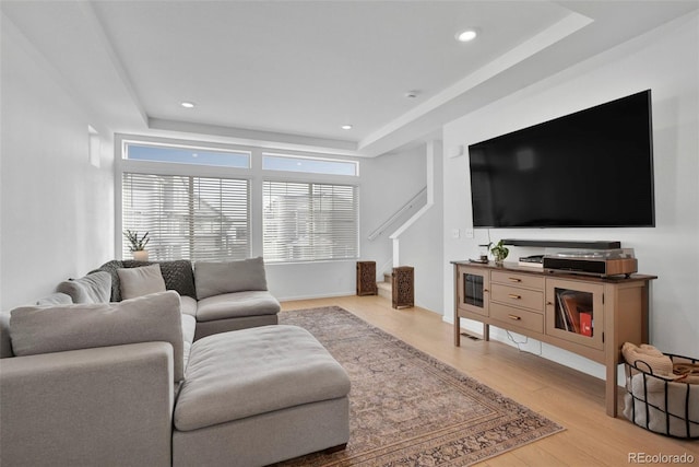 living room with a raised ceiling, wood finished floors, and recessed lighting