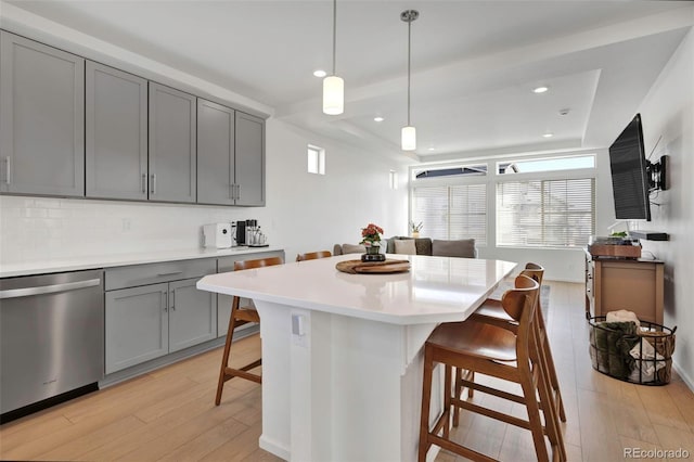 kitchen with a breakfast bar area, gray cabinetry, light wood-style floors, light countertops, and stainless steel dishwasher