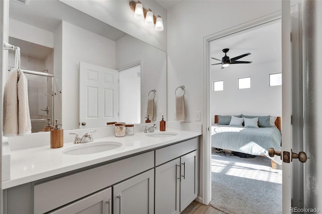 ensuite bathroom featuring a ceiling fan, a stall shower, a sink, and double vanity