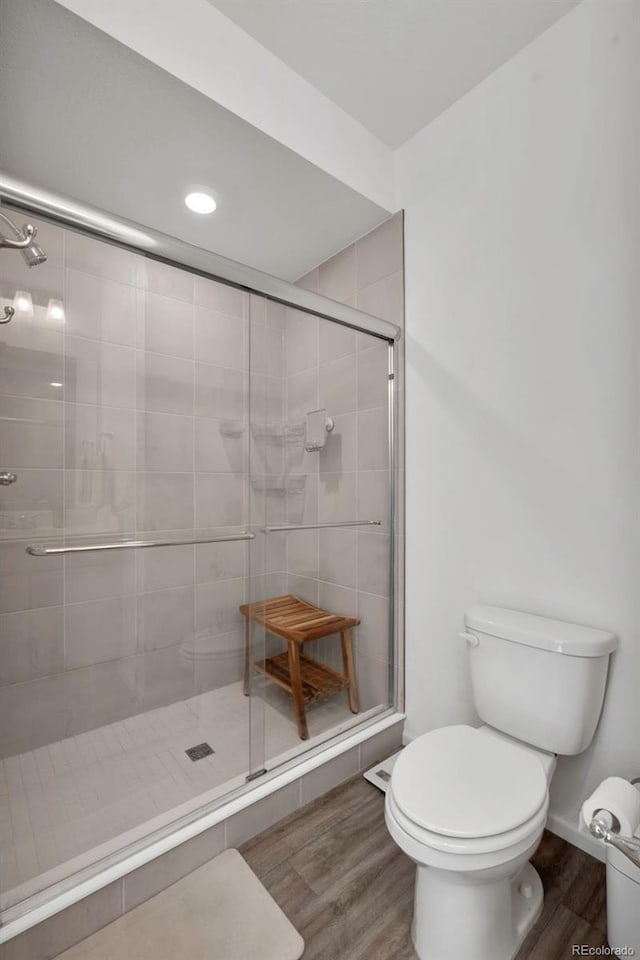 full bath with a shower stall, toilet, and wood finished floors