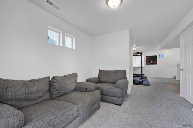 carpeted living area with a wealth of natural light, stairway, and visible vents