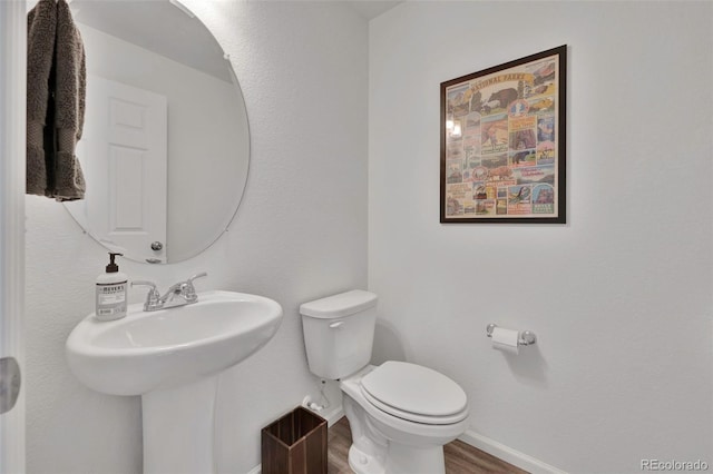 bathroom with a sink, wood finished floors, toilet, and baseboards