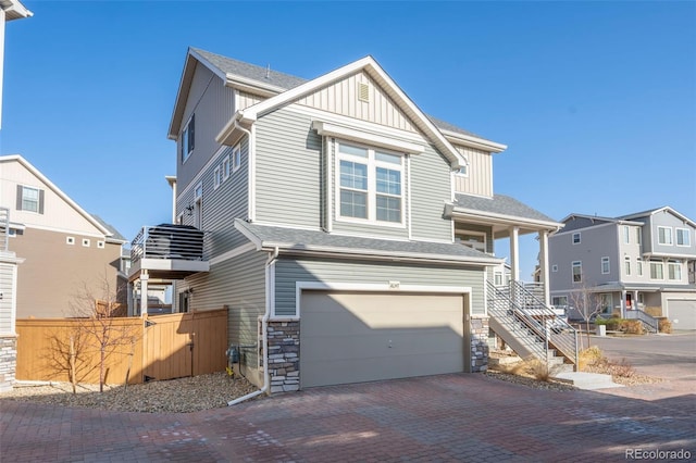 view of front of house with an attached garage, fence, stairway, decorative driveway, and board and batten siding