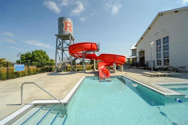 community pool featuring a water slide, a patio area, and fence