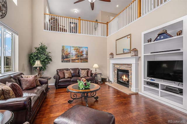 7004 S Addison Ct, Aurora, CO 80016 - living room with ceiling fan, built in shelves, wood-type flooring, a towering ceiling, and a fireplace