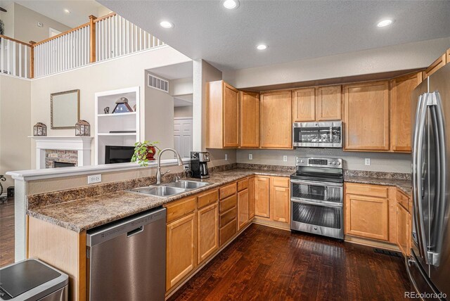 7004 S Addison Ct, Aurora, CO 80016 - kitchen featuring stainless steel appliances, a sink, a stone fireplace, dark wood-style floors, and recessed lighting