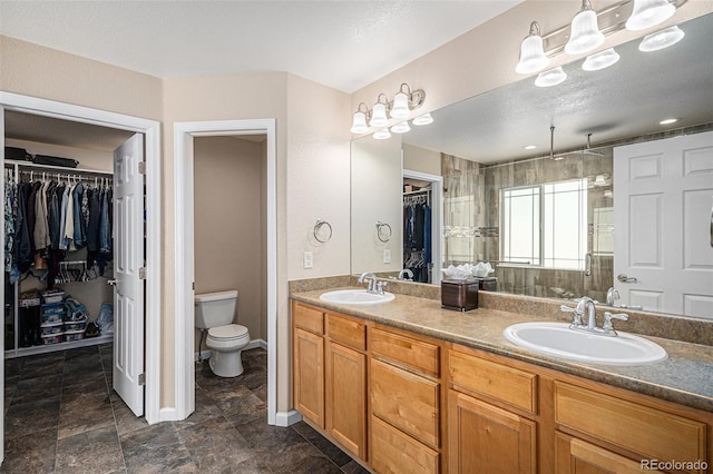 7004 S Addison Ct, Aurora, CO 80016 - bathroom featuring a walk in closet, double vanity, toilet, and a stall shower
