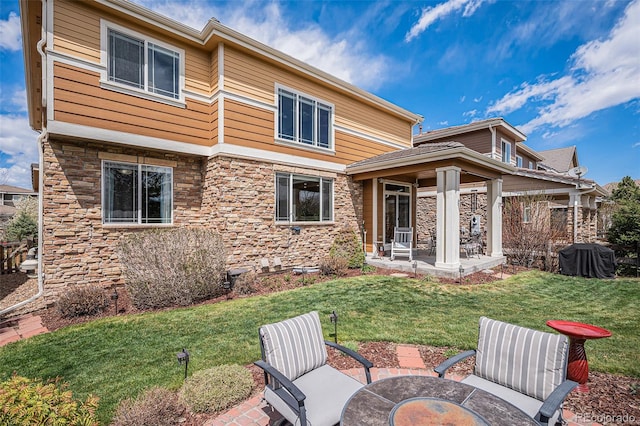 7004 S Addison Ct, Aurora, CO 80016 - back of property with a yard, stone siding, and a patio area