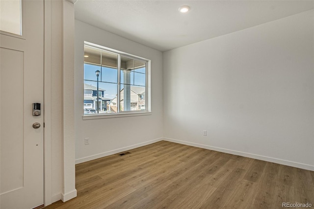 empty room with baseboards, recessed lighting, light wood finished floors, and visible vents