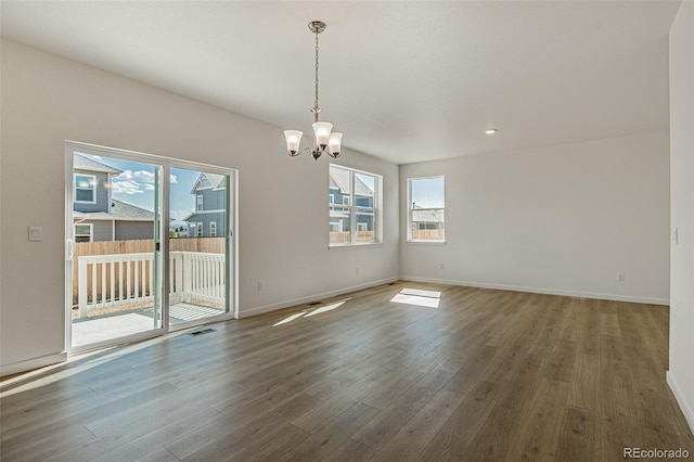 unfurnished dining area with a wealth of natural light, a chandelier, wood finished floors, and baseboards