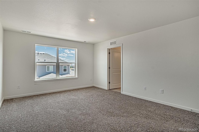 spare room featuring baseboards, carpet flooring, and visible vents