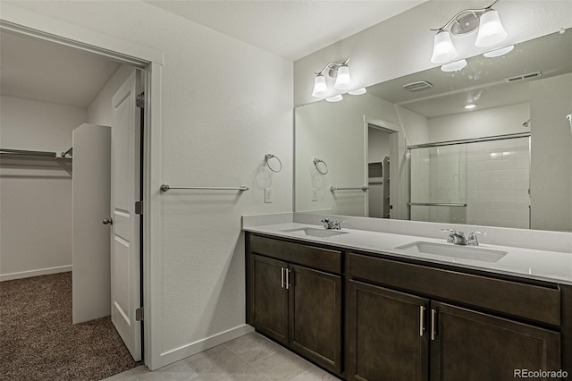 bathroom featuring a sink, a spacious closet, tiled shower, and visible vents