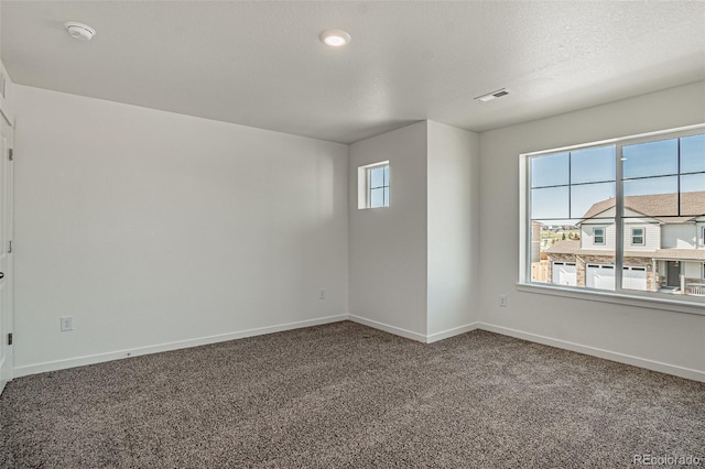 empty room featuring carpet flooring, baseboards, and visible vents