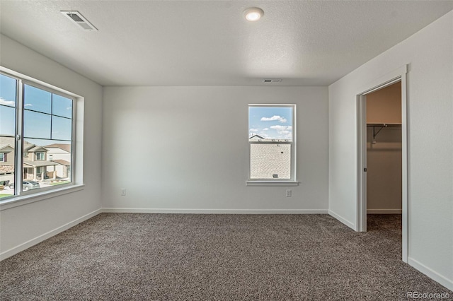 unfurnished bedroom featuring a spacious closet, carpet flooring, and visible vents