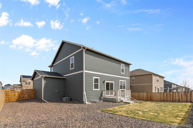 back of property with a yard, a wooden deck, and a fenced backyard